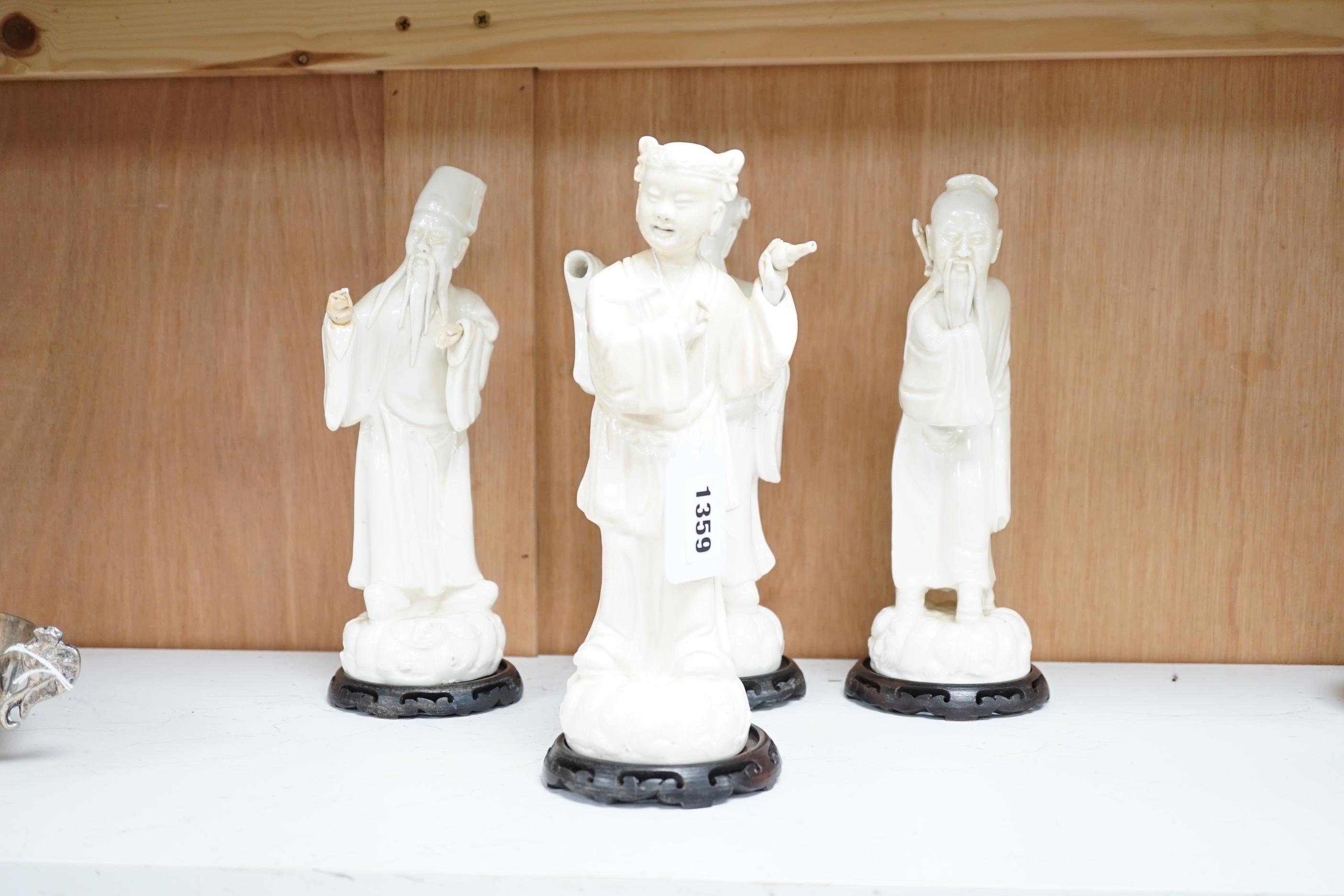 Seven Chinese blanc de Chine figures of immortals, each raised on carved hardwood bases, the largest 24cm high